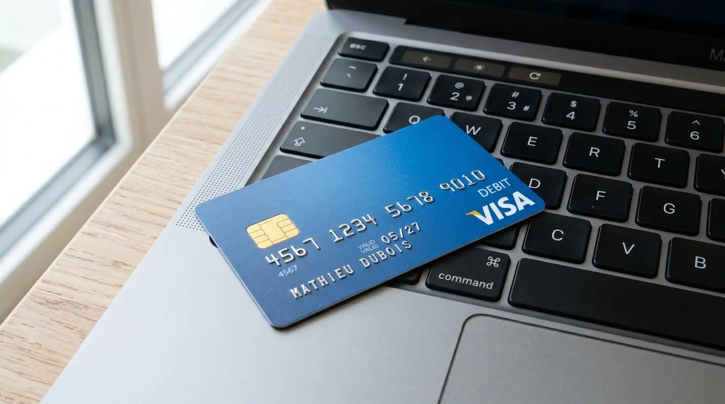 Gros plan d'une carte bancaire Visa moderne posée sur un clavier d'ordinateur portable avec écran flouté en arrière-plan