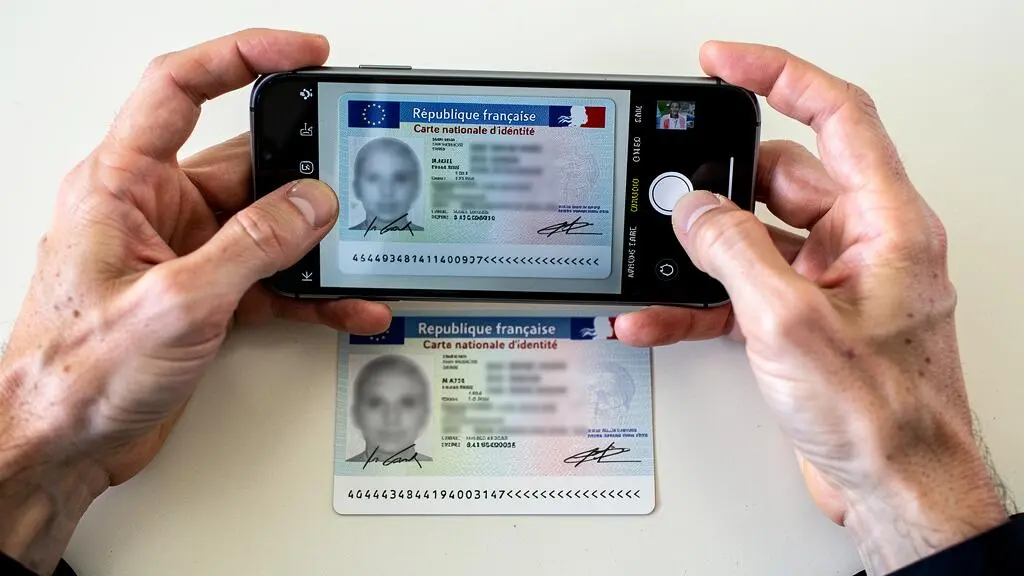 Mains scannant une carte d'identité française avec un smartphone pour l'ouverture d'un compte bancaire en ligne